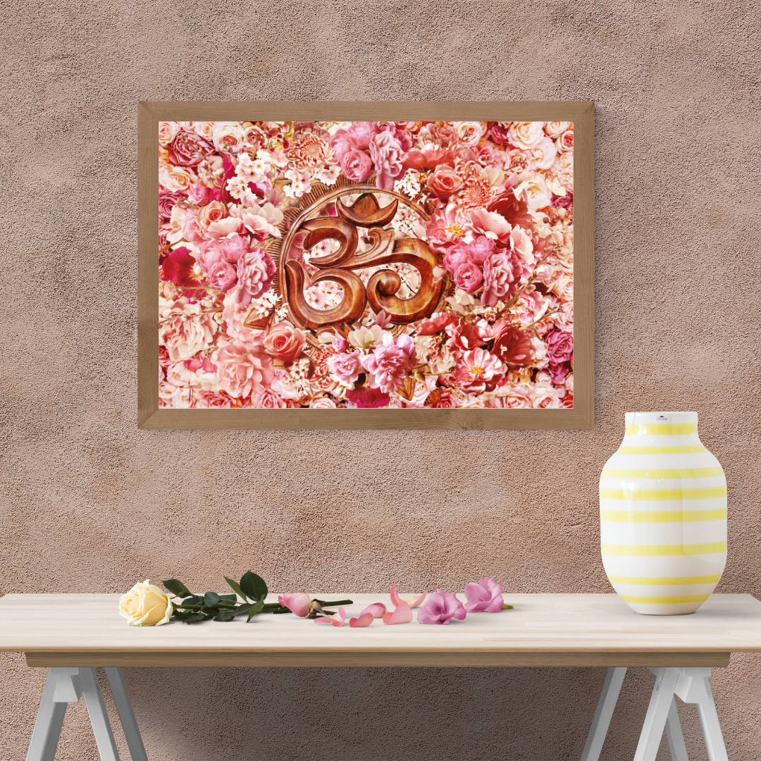 Framed artwork with floral design and 'Om' symbol by dekozi on a wall above a table with flowers and a vase.