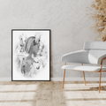 Framed black and white artwork of horses on a wall in a modern interior setting with a chair and decorative plants.