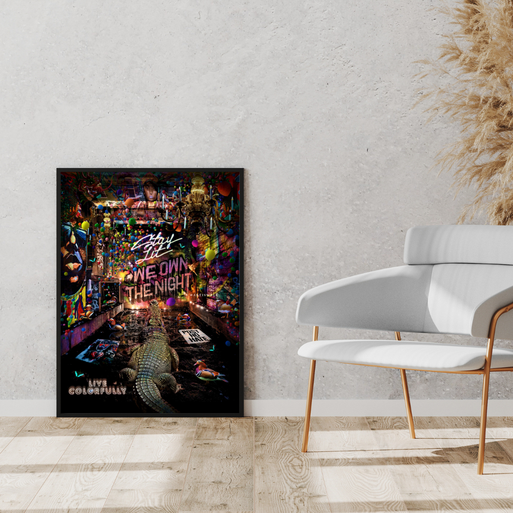 Framed poster of a cityscape with vibrant colors on a wall next to a white chair.