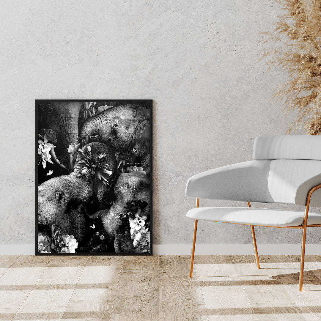 Framed black and white artwork of elephants on a wall above a white chair.