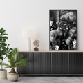Framed artwork of elephants and flowers on a wall above a console table with plants.